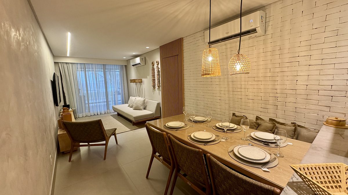 Ambiente integrado com mesa posta, tijolo aparente branco e pendentes de fibra.