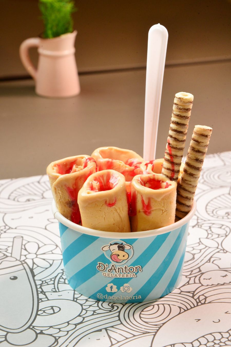 Gelato artesanal enrolado com calda de morango em pote da D'Anton Gelateria.