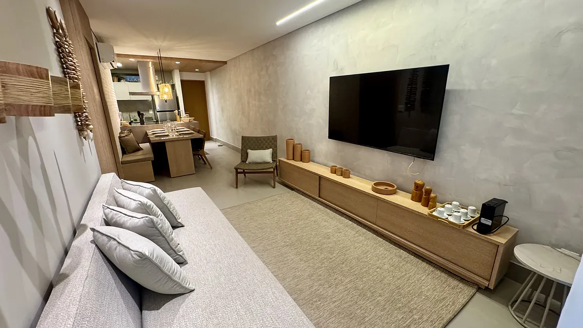 Sala de estar com sof\u00e1 claro, tapete de fibra e marcenaria em madeira ao longo da parede.