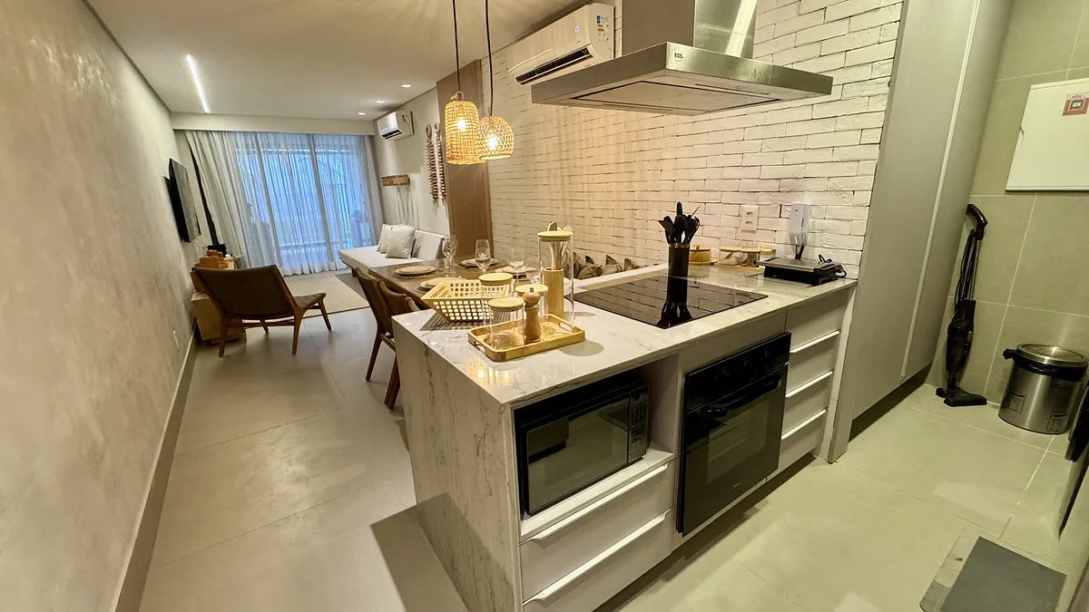 Cozinha com ilha em m\u00e1rmore, forno e cooktop embutidos.