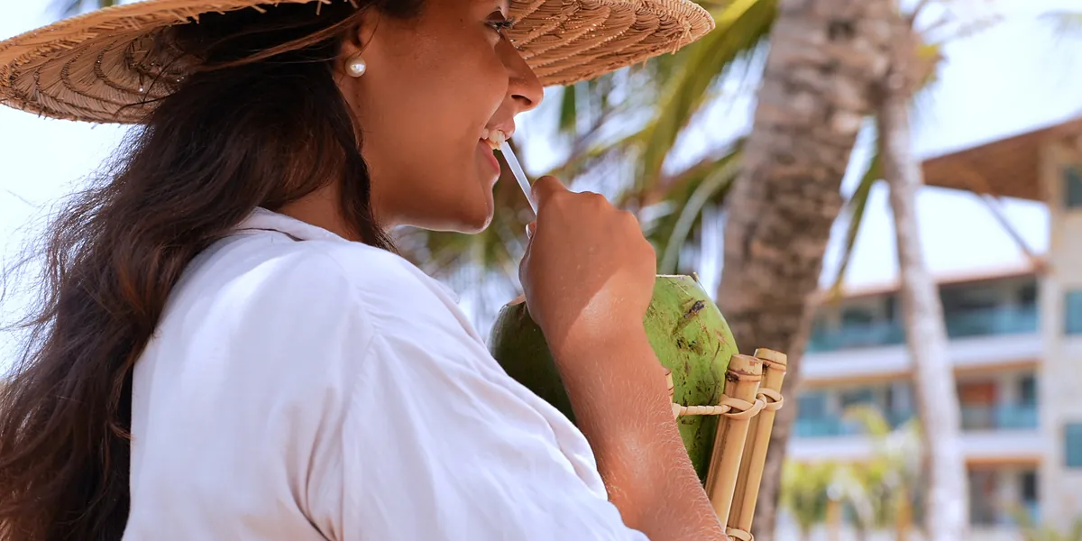 H\u00f3spede com \u00e1gua de coco \u00e0 sombra dos coqueiros.